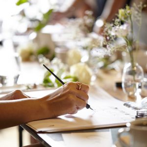 A PERSON HANDWRITING AND LEARNING CALLIGRAPHY AT A LONDON CALLIGRAPHY COURSE IN A BEAUTIFUL SETTING